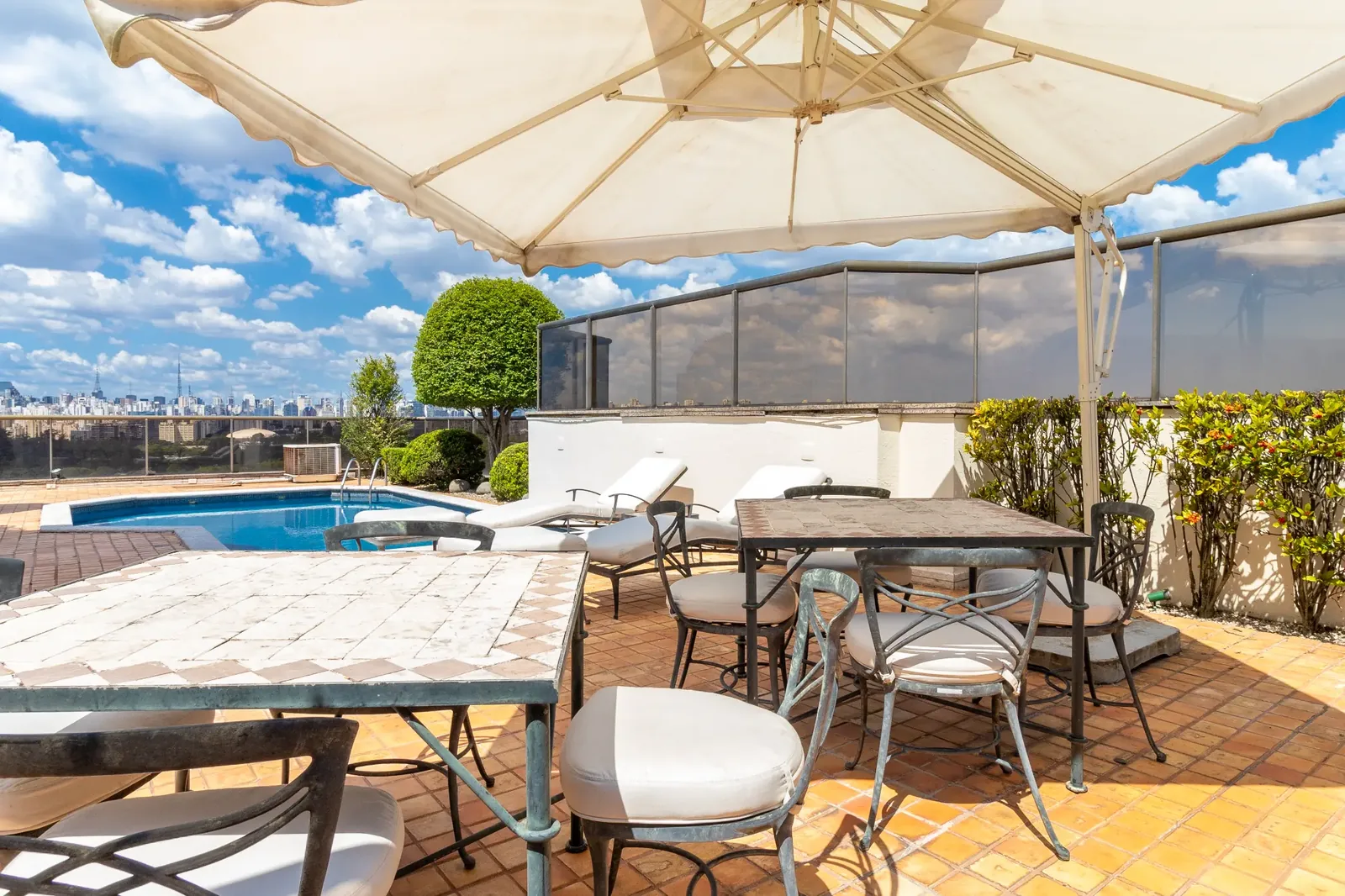 Mesa de convívio, guarda-sol e piscina na área externa atual da cobertura