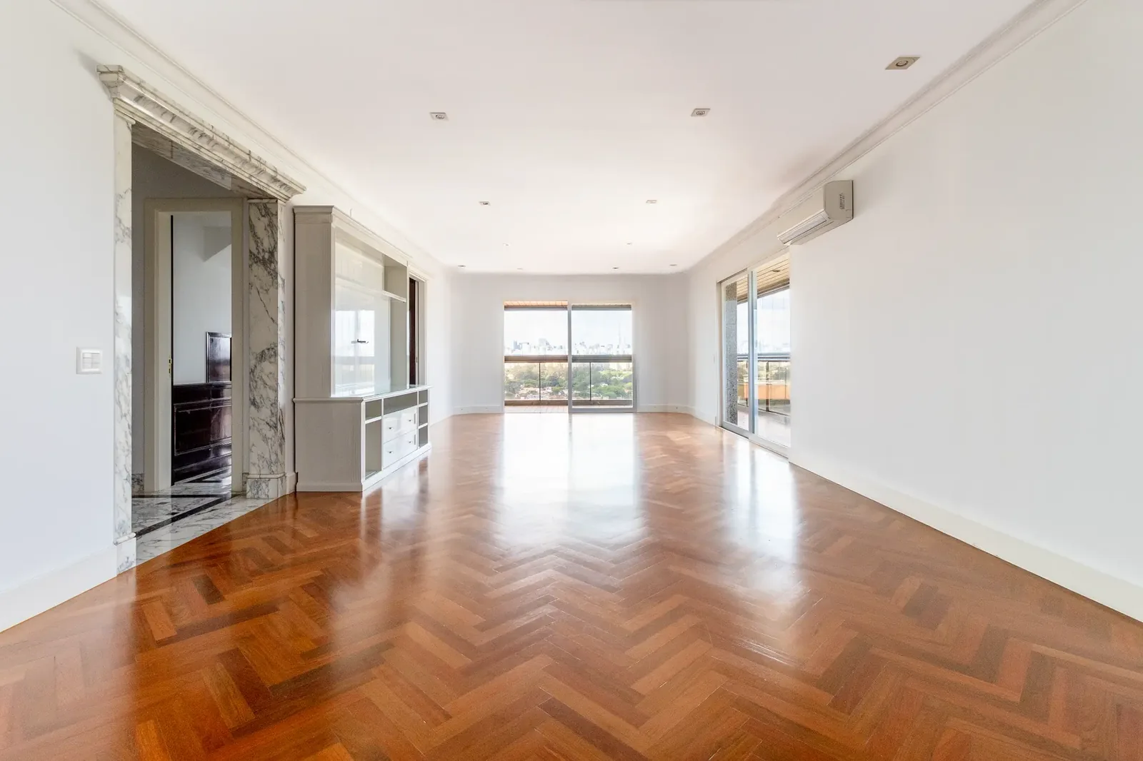 Ambiente interno atual da cobertura com piso de madeira e abertura para o terraço